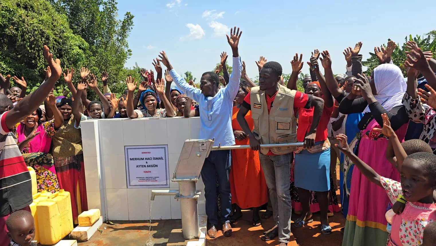 Community members and Zwab team members gather around a handpump.