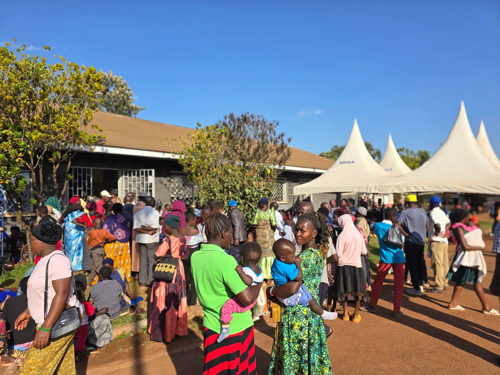 People gather outside tents at a community medical camp.