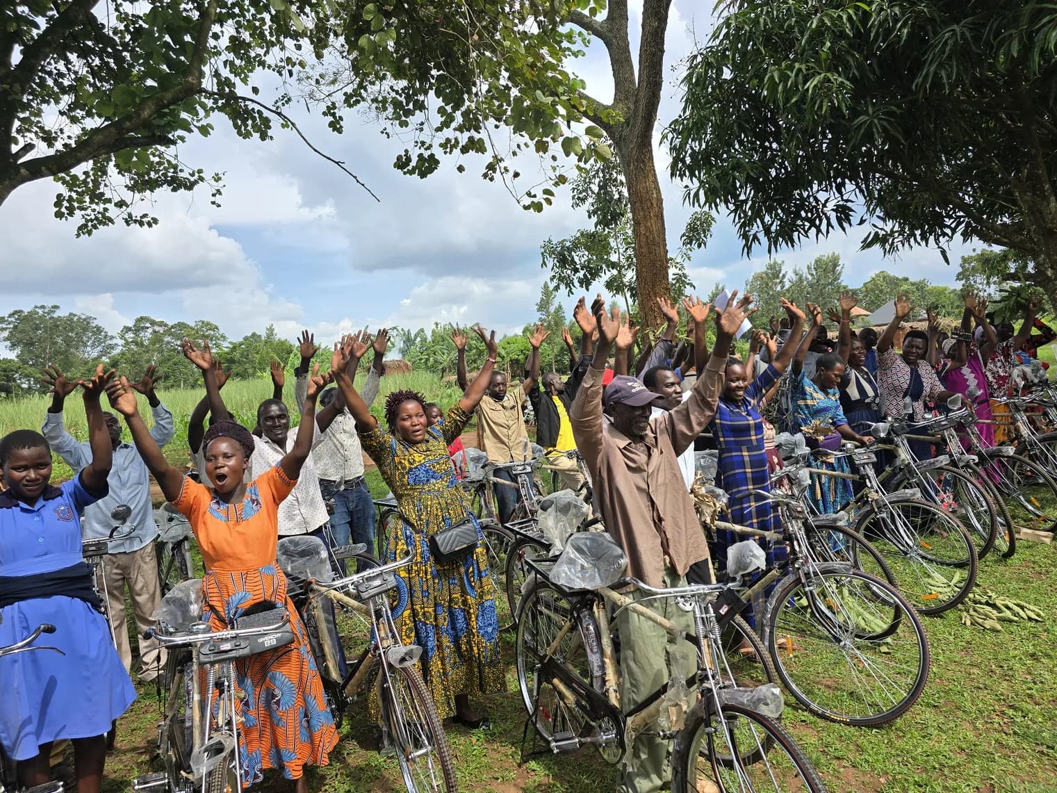 Community members gather with bicycles beneath a tree.