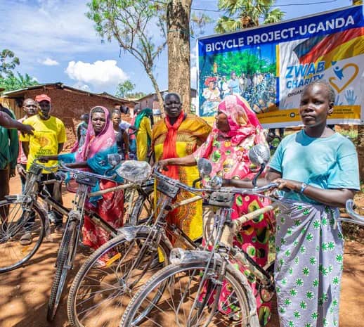 Women stand with bicycles beneath a project banner.