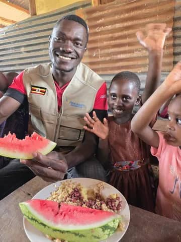A team member stands beside a child with a meal.