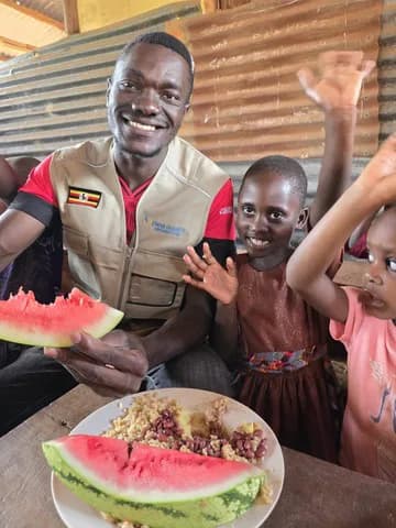 A team member stands beside a child with a meal.