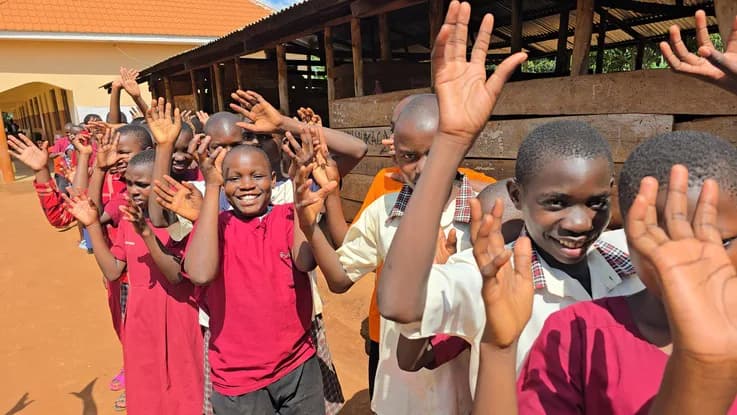 Children wave during an outdoor gathering.