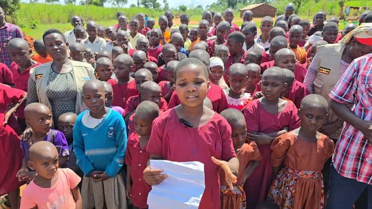 A student holds an exercise book beside classmates.