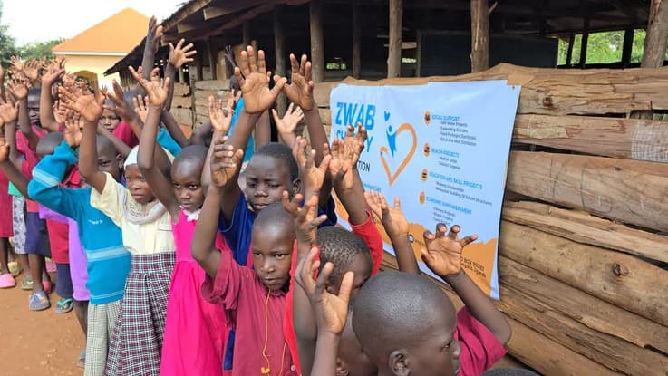 Children raise their hands during an outdoor gathering.