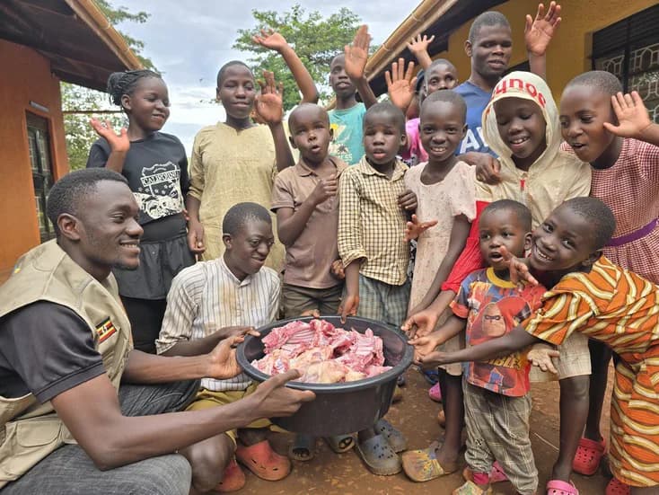Adults and children gather with a bowl of meat.