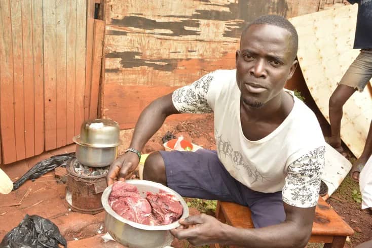 A man holds a plate containing meat.