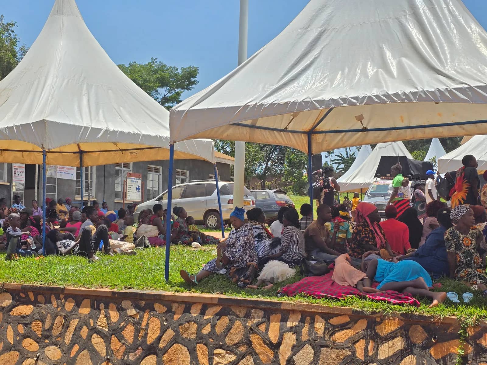 People wait beneath tents at a community medical camp.